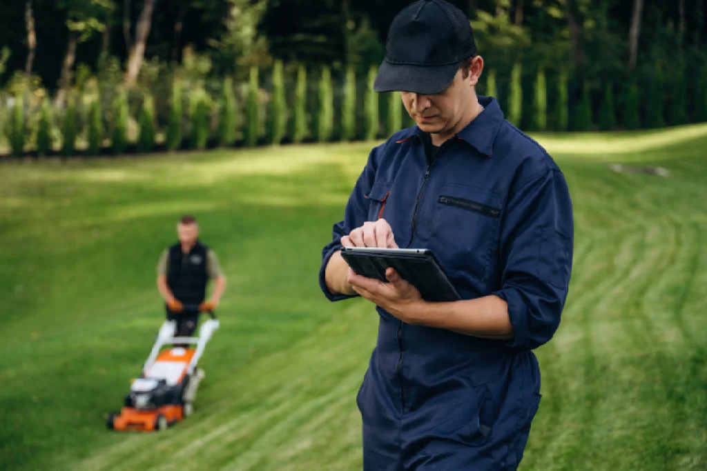 A golf club auditor using a tablet to inspect a green, taking notes on its condition