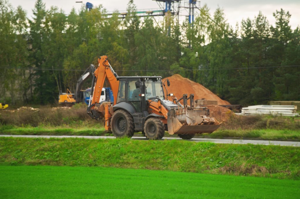 A wide shot of a golf construction site showing heavy machinery performing precision grading on a future fairway.