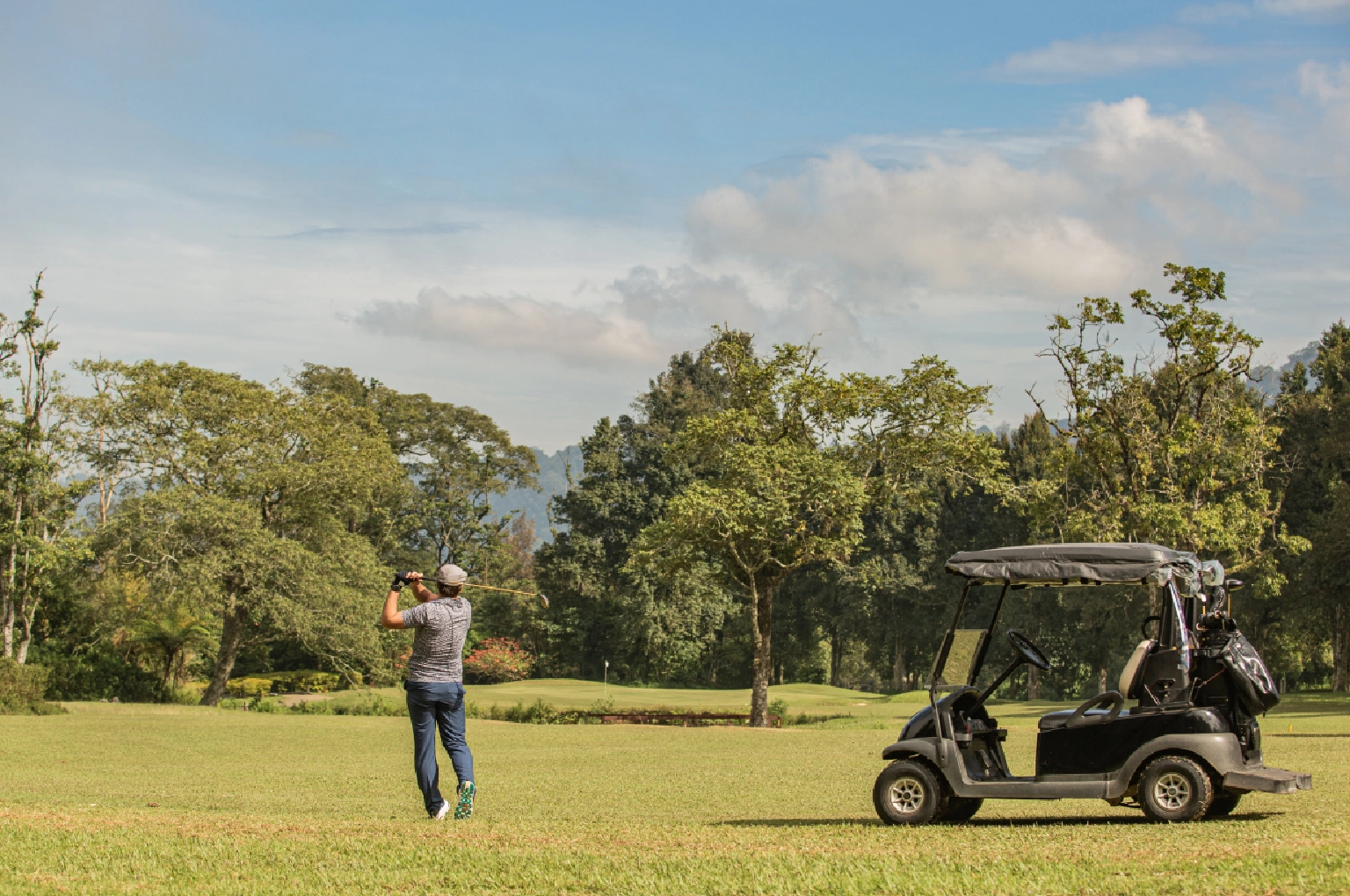A wide shot of a modern golf clubhouse and parking seamlessly integrated with the golf course