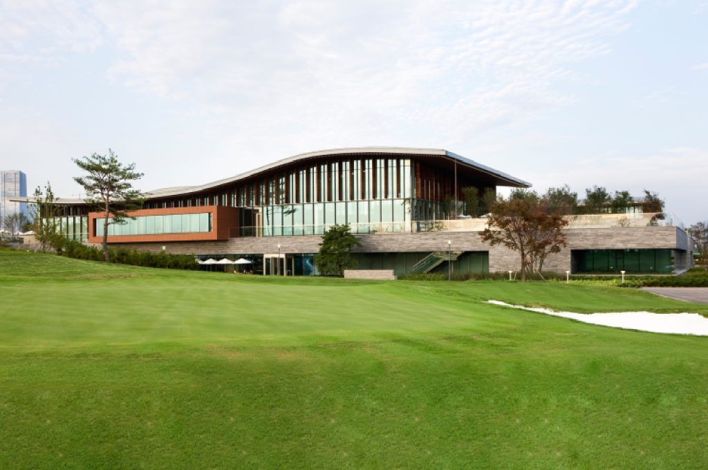 An architectural rendering of a state-of-the-art golf practice facility with covered hitting bays and short game area