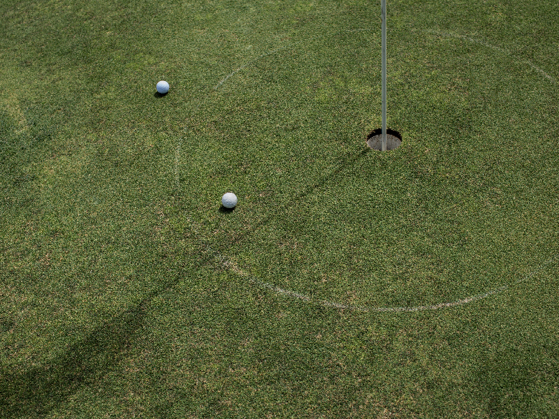 Overhead view of an urban golf course showing the contrast between lush fairways and surrounding city buildings